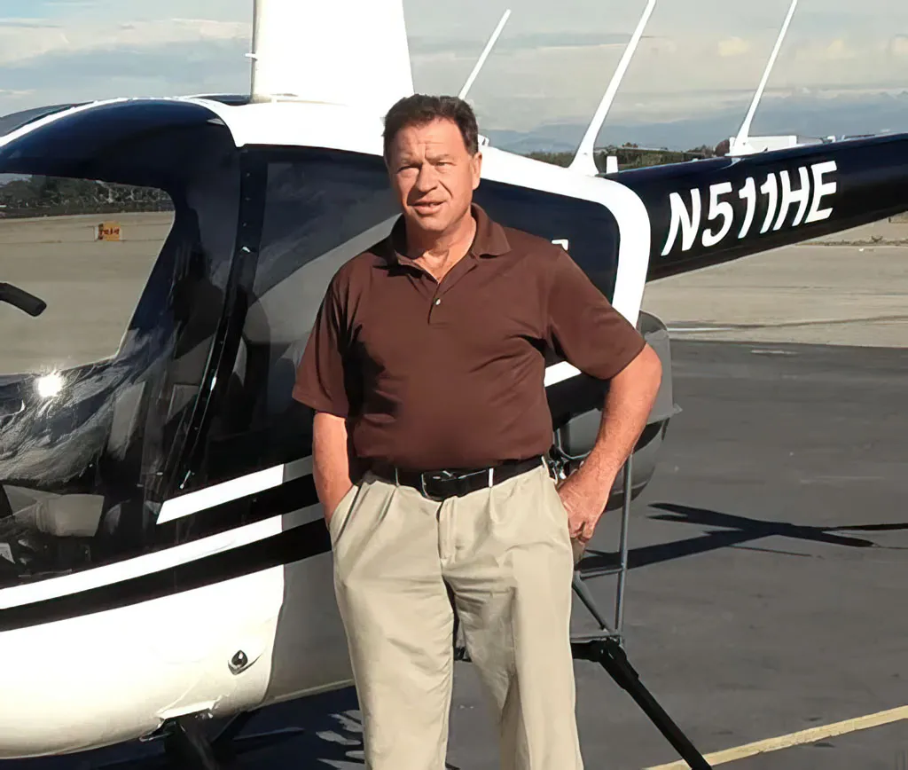 Michael Bisek, founder of Helicopter Experts, standing in front of his Robinson R44 helicopter N511HE