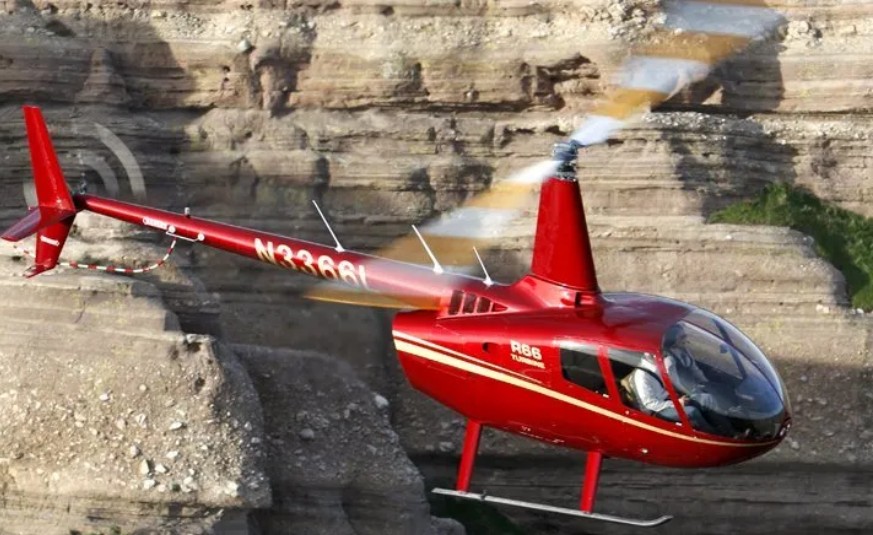 Robinson R-66 Turbine five-seat helicopter in flight along a canyon ridgeline